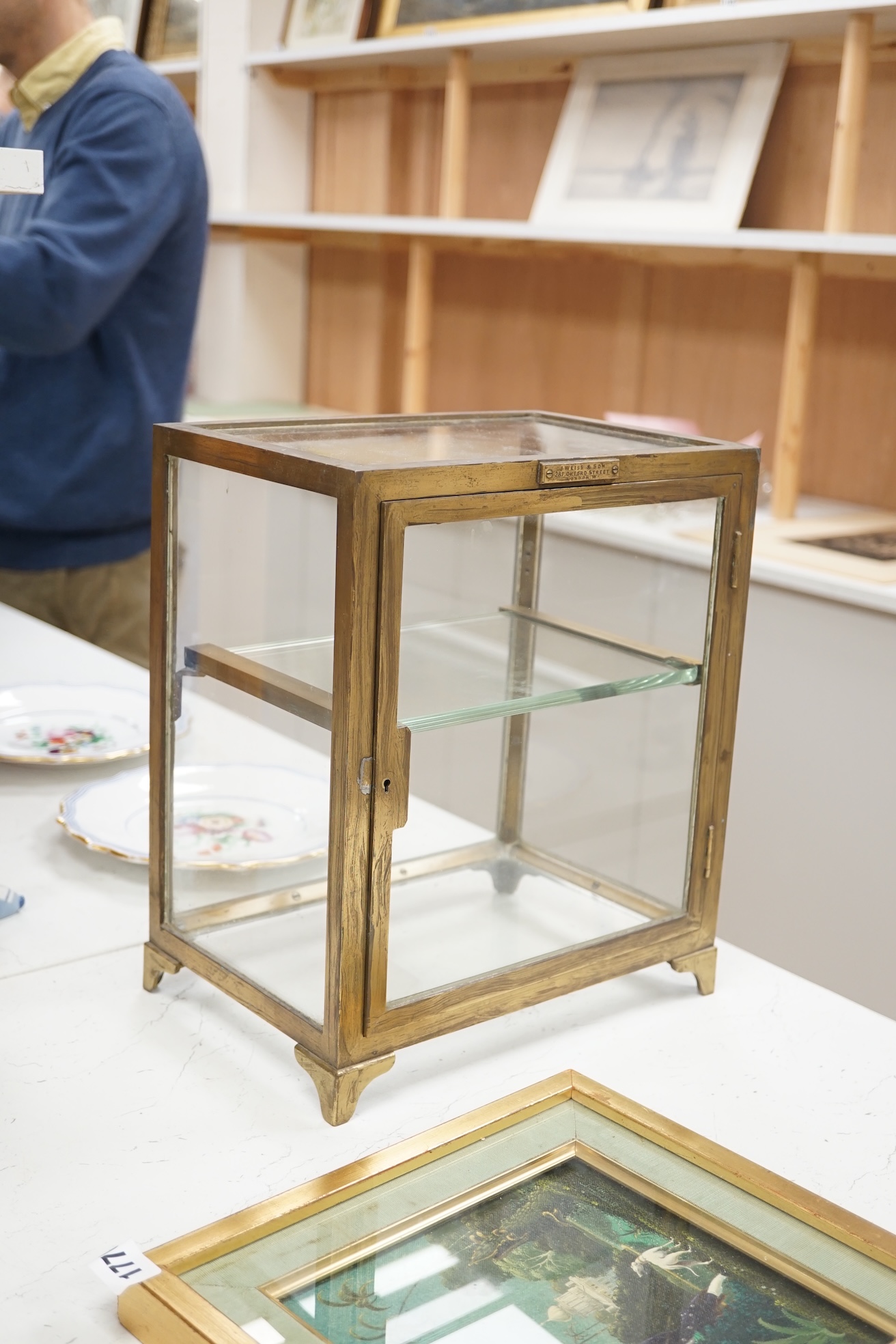 A small late 19th century brass display case, with glass shelf, bears plaque 'J Weiss & Son, 287 Oxford Street, London